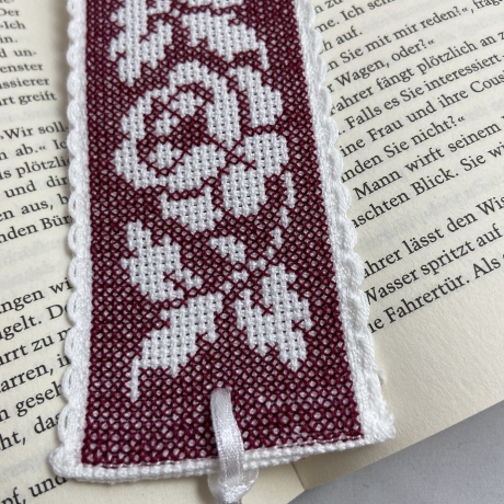 Gesticktes Lesezeichen mit Rosen auf dem Hintergrund in burgund