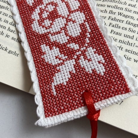 Gesticktes Lesezeichen mit Rosen auf rotem Hintergrund