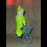 Pierrot in grünem Kostüm auf Fahrrad
